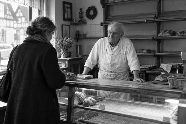 Ein alter Bäcker hinter der fast leeren Theke seiner Bäckerei