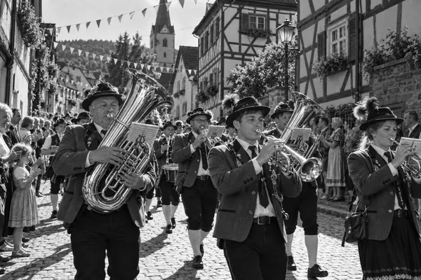 Eine Blaskapelle marschiert durch eine Gasse mit Fachwerkhäusern